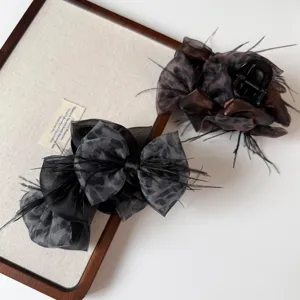 Detail shot of Korean style leopard print bow hair claw with elegant sheer mesh and feather decor.