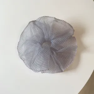 Primer plano detallado de un coletero esponjoso y transparente con lunares para el cabello.