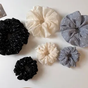 Vista dettagliata di scrunchies per capelli di vari colori con delicato motivo a fiocco.