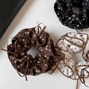 Close-up detail of vintage Korean floral scrunchies with long ribbon ties and ruffled edges.