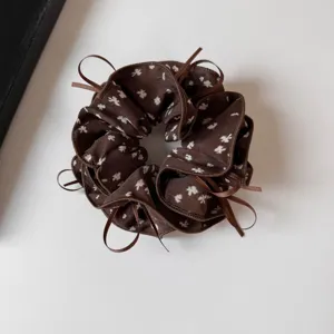 Close-up detail of retro brown floral hair scrunchie with cute ribbon ties and pleated design.