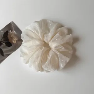 Primo piano dettagliato di un elastico per capelli in rete bianca con delicati fiocchi.
