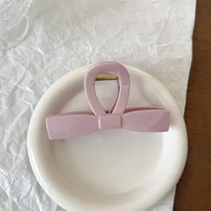 Primo piano di una molletta per capelli in acrilico rosa a forma di fiocco con molla.