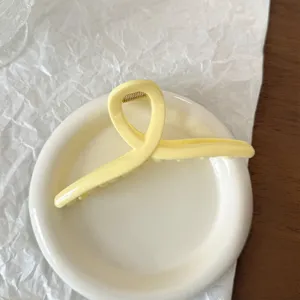 Primo piano di dettaglio di una elegante molletta per capelli in acrilico giallo su piatto.