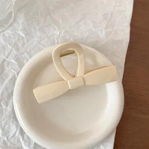 Primo piano di elegante molletta per capelli in acrilico beige con fiocco e finitura liscia.