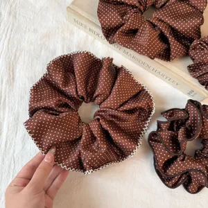 Brown polka dot hair scrunchie detail shot, elegant ruffled elastic hair tie for women.