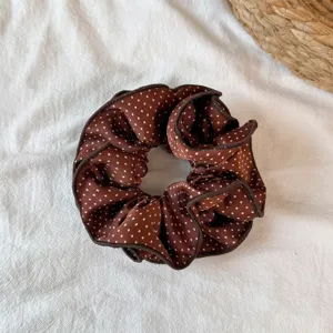 Brown polka dot hair scrunchie with ruffled edge, stylish fabric hair tie for daily use.