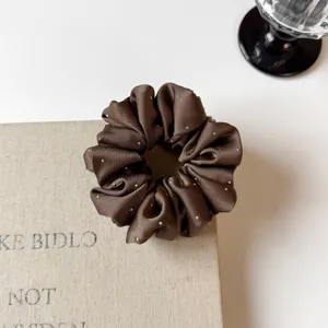 Close-up detail of dark brown satin hair scrunchie sparkling with tiny silver crystals.