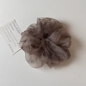 Vue rapprochée d'un chouchou en organza dégradé gris foncé avec une texture scintillante.