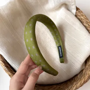 Green polka dot wide fabric headband detail view, showing delicate handmade hair accessory.