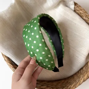Green polka dot headband detail shot, stylish wide design, lightweight fabric hair accessory.