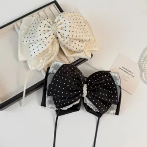 Gedetailleerd overzicht van chiffon kanten strik haarclips met elegante zwart-witte stippen.