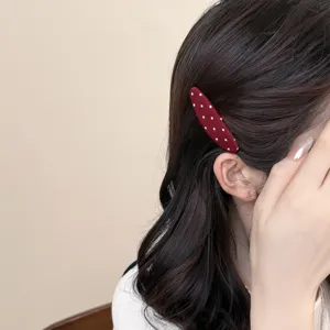 Close-up detail shot of a cute red polka dot snap hair clip worn on dark hair.