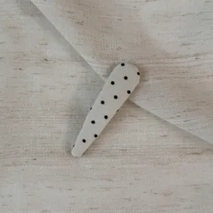 Detail view of a cute polka dot fabric snap clip, perfect for styling side bangs and hair.