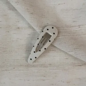 Close-up of a cute beige polka dot fabric snap hair clip, perfect for styling bangs.