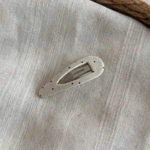 Primer plano detalle de la horquilla BB de tela de lunares con textura y broche metálico.