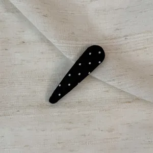 Close-up of black white polka dot snap hair clip, cute Korean style hair accessory detail.