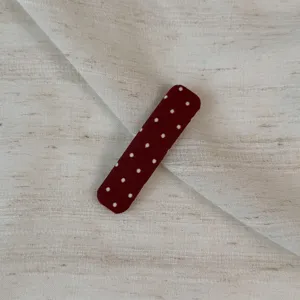 Dark red polka dot snap hair clip detail view, showcasing the cute fabric-wrapped design.