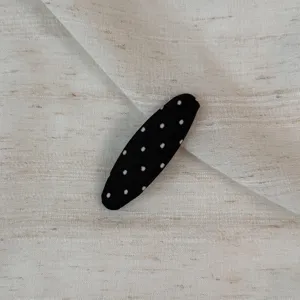 Black and white polka dot fabric snap hair clip detail close-up view, chic cute style.