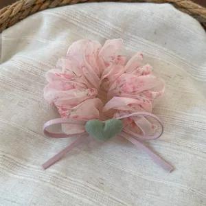 Scrunchie per capelli in rete floreale estiva con cuore verde e nastro decorativo.
