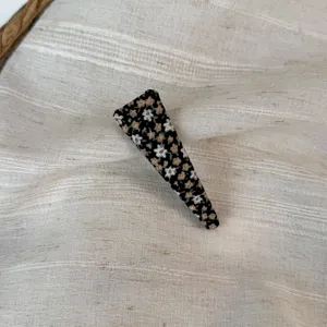 Detailed shot of a floral fabric hair clip with black background, sweet and elegant style.