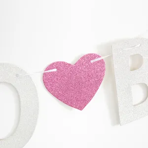 Close-up of pink glitter heart and silver letters on bachelorette party banner decoration.
