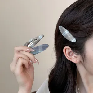 Plaid snap hair clip detail showcasing grey fabric design, elegant fringe styling accessory.