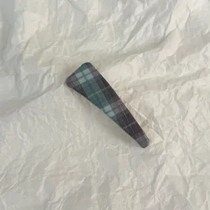 Close-up detail of blue plaid snap hair clip, stylish fabric hair accessory for daily wear.