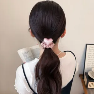 Roze satijnen polkadot hart haarelastiek detailopname toont fijne stoftextuur voor haaraccessoire.
