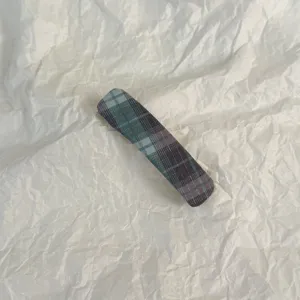 Detail view of the classic plaid snap hair clip, showing fine fabric texture and neat stitching.