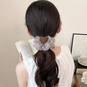 Λεπτομέρεια από αφράτο scrunchie οργάντζας με καφέ καρδιά, ιδανικό για κομψά χτενίσματα.