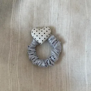 Gedetailleerd overzicht van de grijze satijnen haarring met een schattig zwart-wit hart.