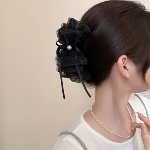 Detail view of black mesh bow hair claw, delicate lace edge and pearl charm for elegant style.