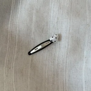 Detailopname van een mooie zwarte BB-haarspeld met een wit hart en zwarte stippen.