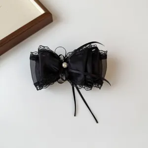 Close-up of a delicate black lace mesh bow hair clip featuring a central pearl.