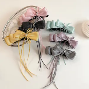 Detail shot of elegant satin bow hair claw clips with flowing ribbons, multiple chic colors.