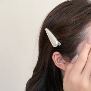 Nahaufnahme Detail einer minimalistischen, glänzenden metallischen Welle Haarspange seitlich.