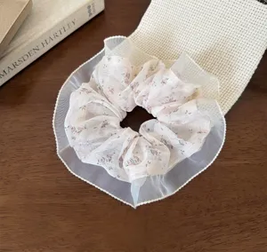 Chiffon floral scrunchie with delicate white lace ruffle trim, detail view of fabric texture.
