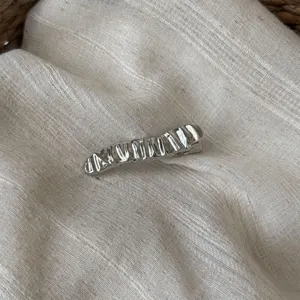 Nahaufnahme der silbernen metallischen Wellen-Haarspange mit feiner Textur und Glanz.
