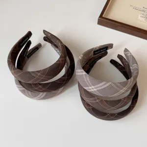 Detalle de diadema a cuadros marrón, banda para el pelo acolchada estilo colegial.