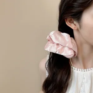 Glanzend satijnen haarelastiek detail met zachte roze textuur en elegant haaraccessoire.