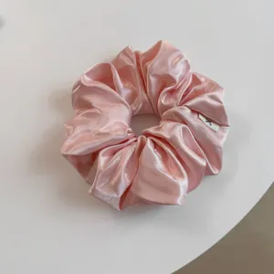 Elegante roze saten haarscrunchie met glanzende afwerking, perfect voor stijlvolle dagelijkse looks.