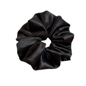 Elegante zwarte satin scrunchie met glanzende afwerking voor een veilige en stijlvolle haarstyling.