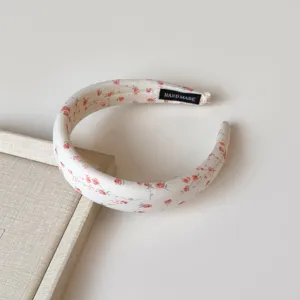 Vista detallada de la diadema de tela floral dulce, que muestra un delicado diseño rosa.