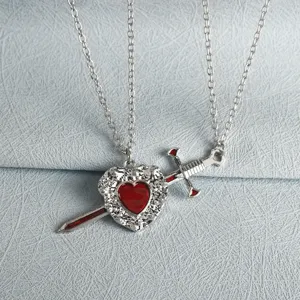 Detailed close-up of gothic heart and dagger pendant necklace, antique silver tone metal.