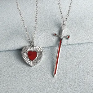 Close-up detail of the creative couple heart and sword necklace set, stylish metal design.