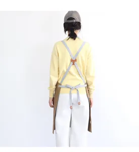 Back view details of cross-back canvas apron with durable straps and leather connectors.