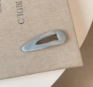 Dettaglio molletta per capelli in raso delicato, elegante accessorio azzurro laterale chic.