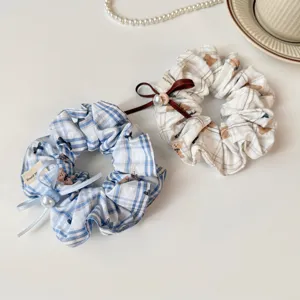 Close-up detail of cute plaid and bear print hair scrunchie with bow and pearl decor.