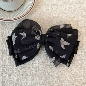 Primo piano dettagliato del fiocco per capelli in chiffon nero con stampa di farfalle.